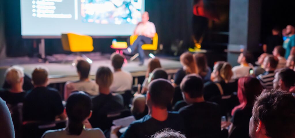 A room of people await a talk